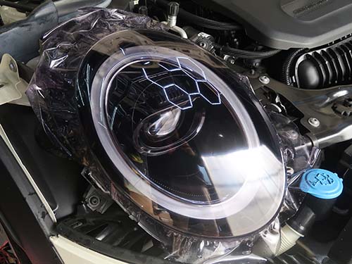 ヘッドライトレンズへ専用のプロテクションフィルムを貼り付け